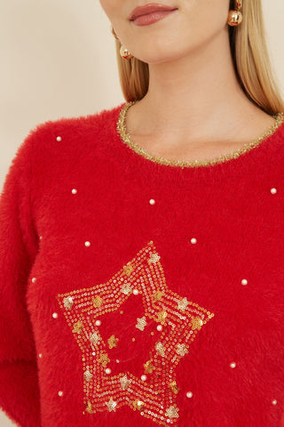 Close-up of a red knitted fluffy Christmas star jumper with gold sequin star embellishment and pearl details