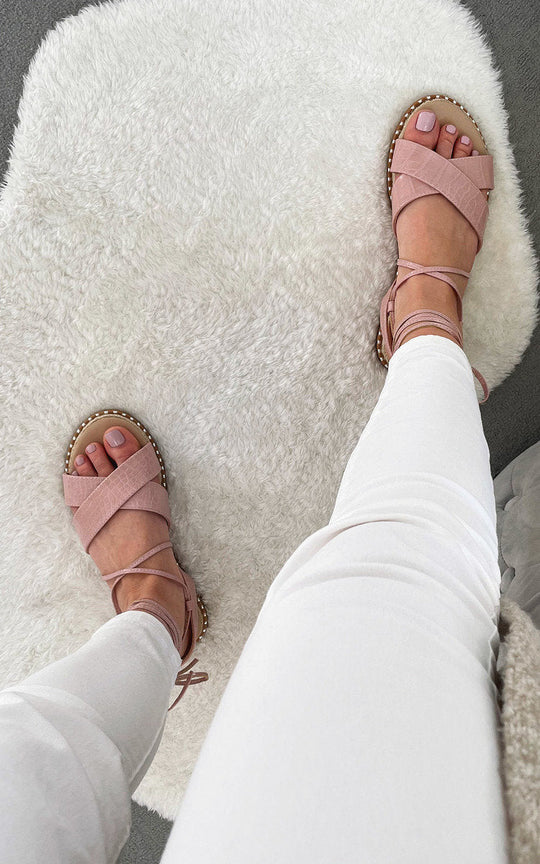 Deja Strappy Sandals in chic pink on white fur rug.